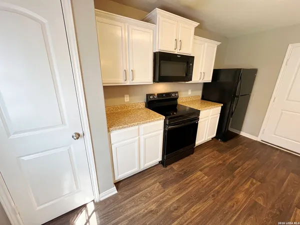 a kitchen with a sink wooden floor and black appliances