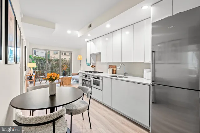 a kitchen with stainless steel appliances granite countertop a stove a refrigerator a sink a dining table and chairs