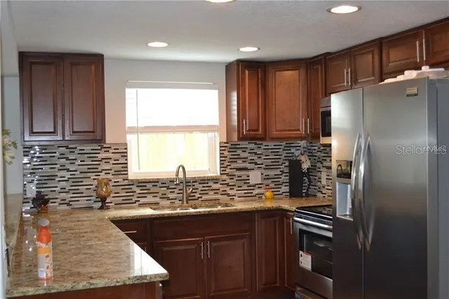 a kitchen with stainless steel appliances granite countertop a refrigerator and a sink