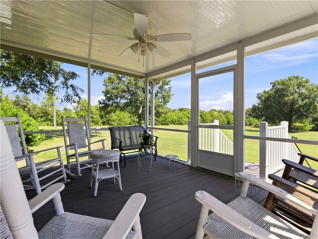 A spacious screened porch looks out over peaceful, tree-lined green acreage.