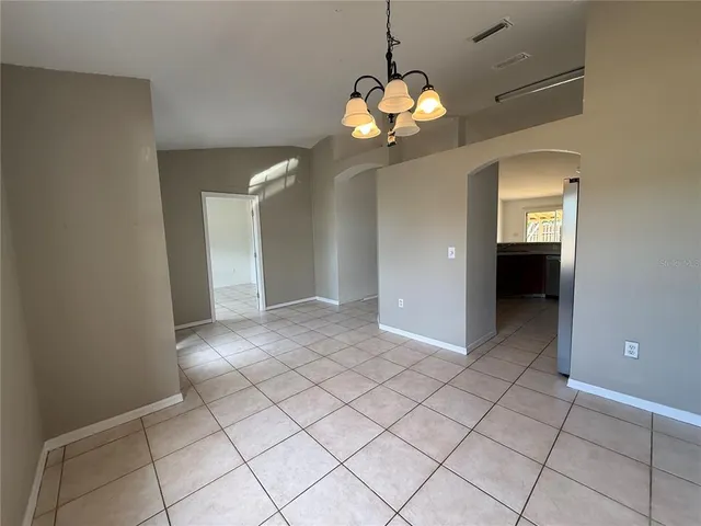 an empty room with chandelier and glass door