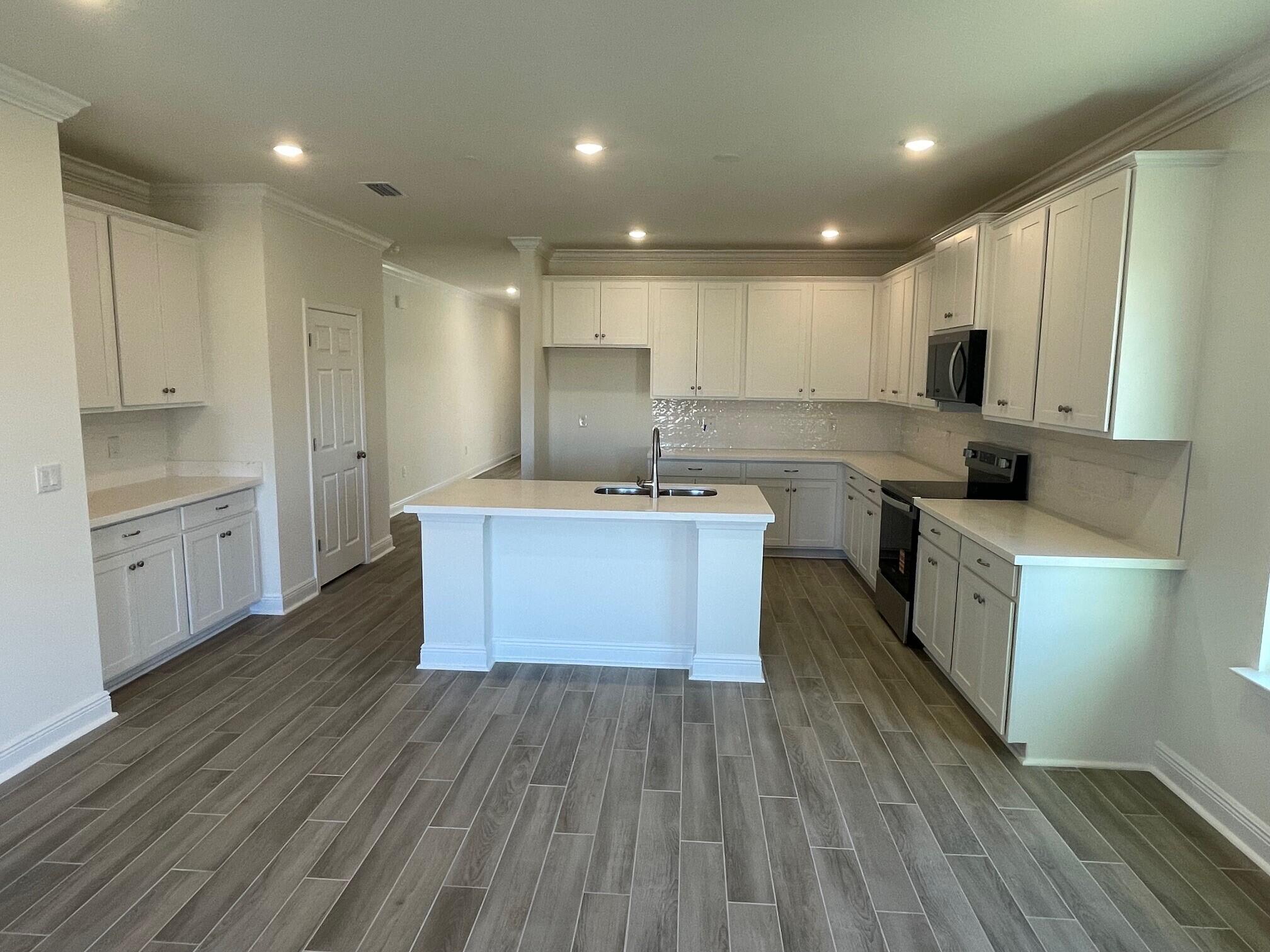 23 Splendor Run Ponce de Leon, FL 32455 - Photo 3 of 8 a large kitchen with stainless steel appliances granite countertop a white cabinets a sink dishwasher and a stove with wooden floor