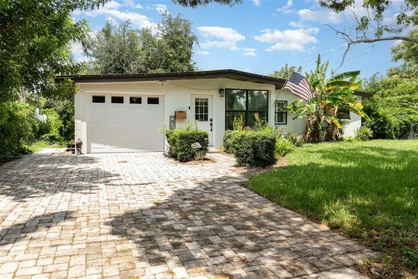 a front view of a house with a yard and potted plants