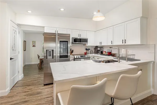 a living room with stainless steel appliances furniture a dining table and chairs