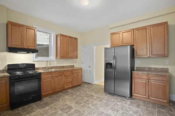 a kitchen with granite countertop a refrigerator stove top oven and sink