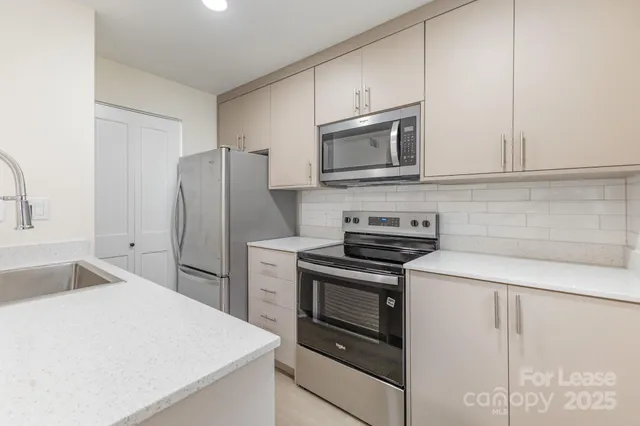 a kitchen with stainless steel appliances white cabinets and a refrigerator