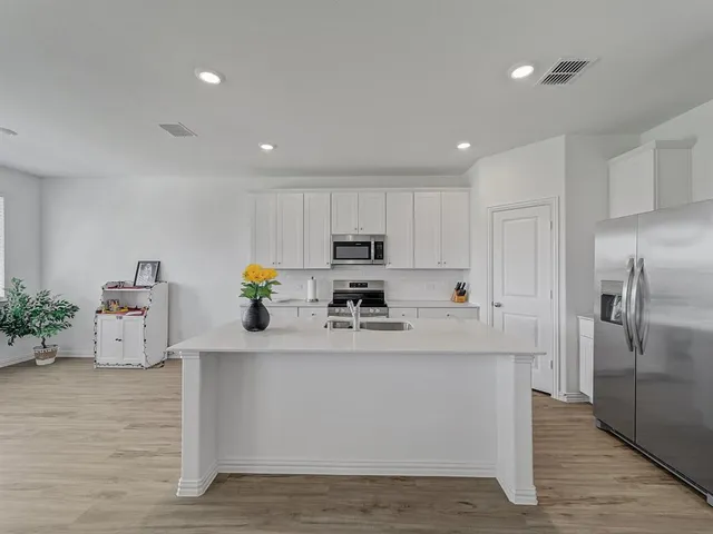 a kitchen with stainless steel appliances a sink a stove a refrigerator cabinets and living room view