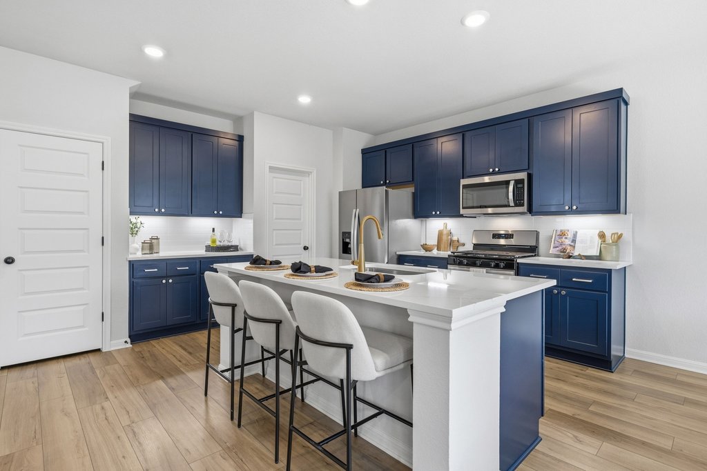 8001 Andravida Drive Austin, TX 78747 - Photo 3 of 35 Kitchen featuring a kitchen breakfast bar, a kitchen island with sink, navy blue cabinetry, stainless steel appliances, and recessed lighting