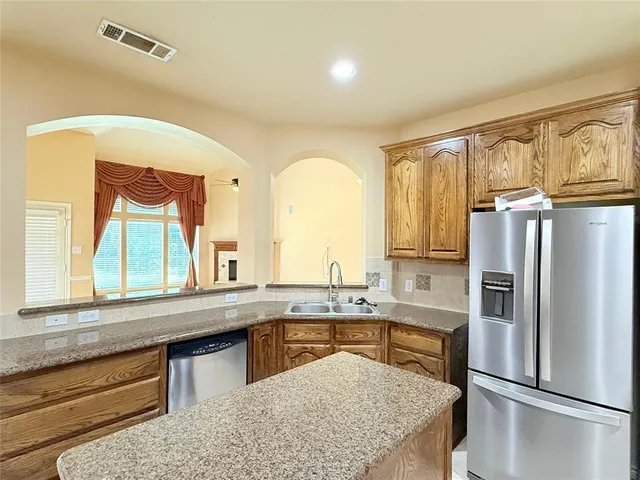 a kitchen with stainless steel appliances granite countertop a refrigerator a sink and white cabinets