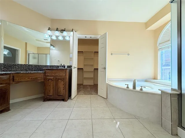 a bathroom with a granite countertop sink a large mirror and a wooden cabinets