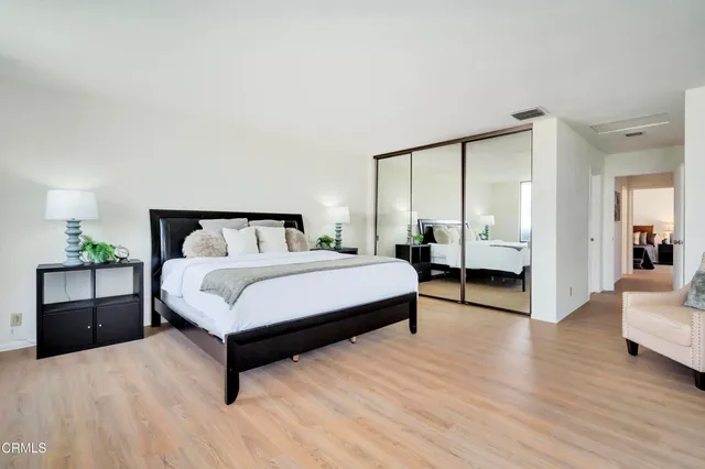 a spacious bedroom with a bed and wooden floor