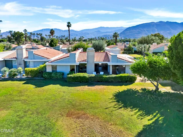 a view of a white house with a big yard and large trees