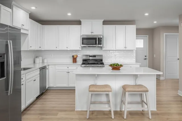 a kitchen with stainless steel appliances granite countertop a stove a sink dishwasher and a refrigerator with wooden floor