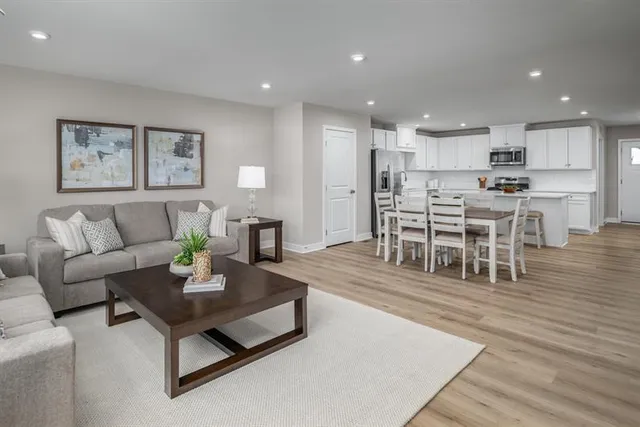 a living room with furniture and a dining table with wooden floor
