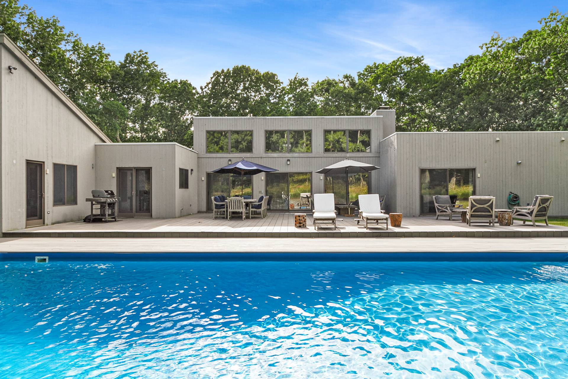 1705 Noyack Road Southampton, NY 11968 - Photo 2 of 16 a front view of a house with swimming pool having outdoor seating