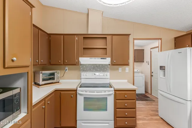 a kitchen with granite countertop a refrigerator stove and cabinets