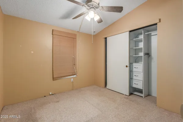 an empty room with closet and fan