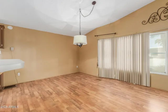 a view of a room with a hanging light and kitchen space