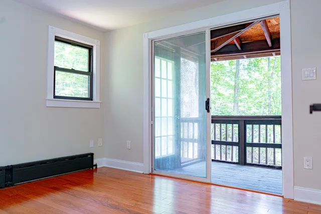 a view of an empty room with wooden floor and a window