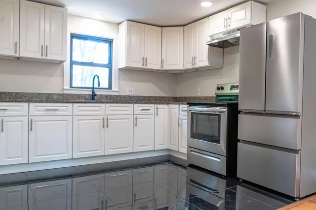 a kitchen with granite countertop white cabinets and stainless steel appliances