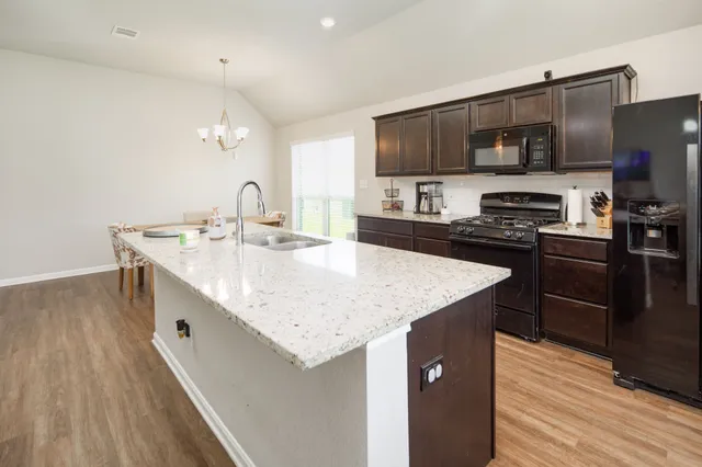a kitchen with stainless steel appliances granite countertop a sink a microwave a refrigerator and cabinets