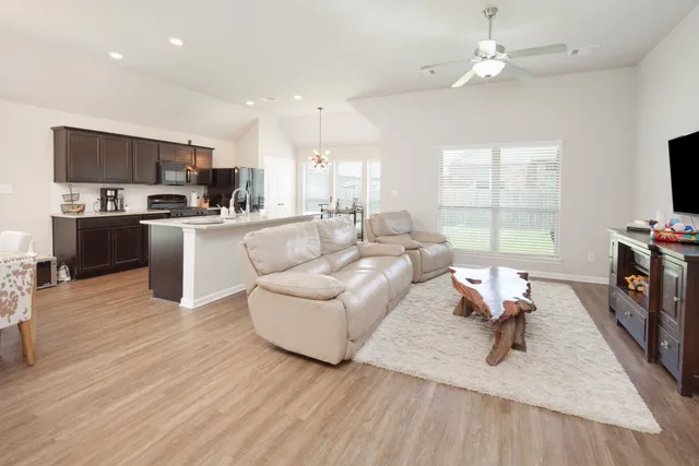 a living room with furniture a flat screen tv and kitchen view