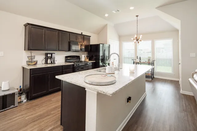 a kitchen with stainless steel appliances granite countertop a sink a stove and a wooden floors