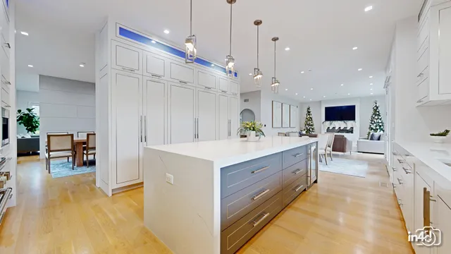 a large white kitchen with wooden floor and a chandelier