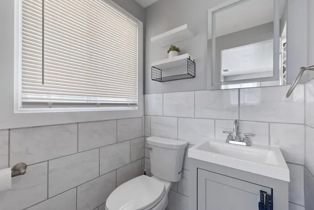 a bathroom with a toilet sink vanity and mirror
