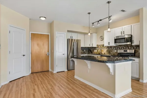 a large kitchen with stainless steel appliances granite countertop a stove a sink and a wooden floor