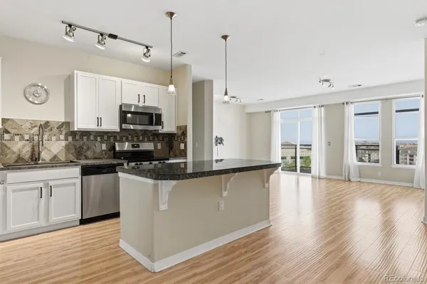 a kitchen with stainless steel appliances granite countertop a refrigerator a stove a microwave oven a sink with cabinets and wooden floor