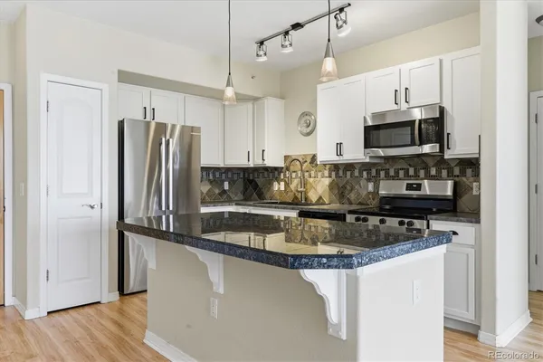 a kitchen with stainless steel appliances granite countertop a refrigerator a sink and a oven