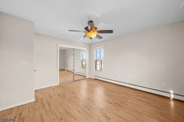 a view of an empty room with window and wooden floor