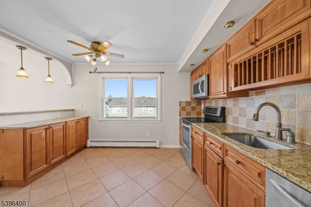 a kitchen with stainless steel appliances granite countertop a sink a stove cabinets and a window