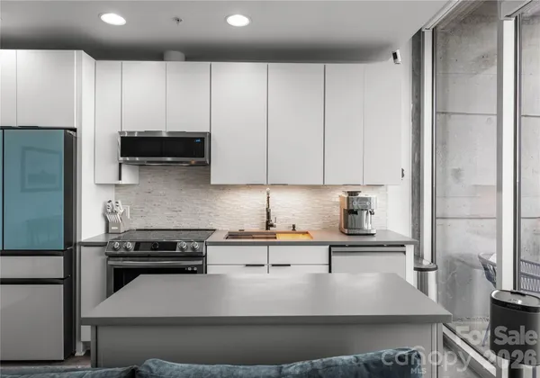 a kitchen with kitchen island granite countertop a sink a stove and a refrigerator