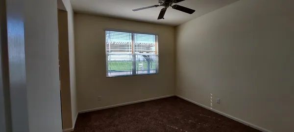 an empty room with a chandelier fan and windows