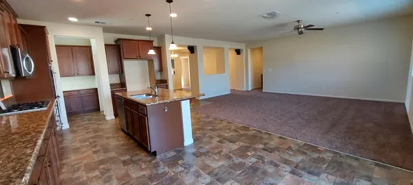 a large kitchen with stainless steel appliances kitchen island granite countertop a refrigerator and a sink