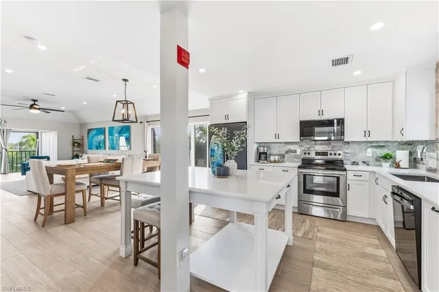 a kitchen with stainless steel appliances granite countertop a stove top oven a sink dishwasher a dining table and chairs with wooden floor