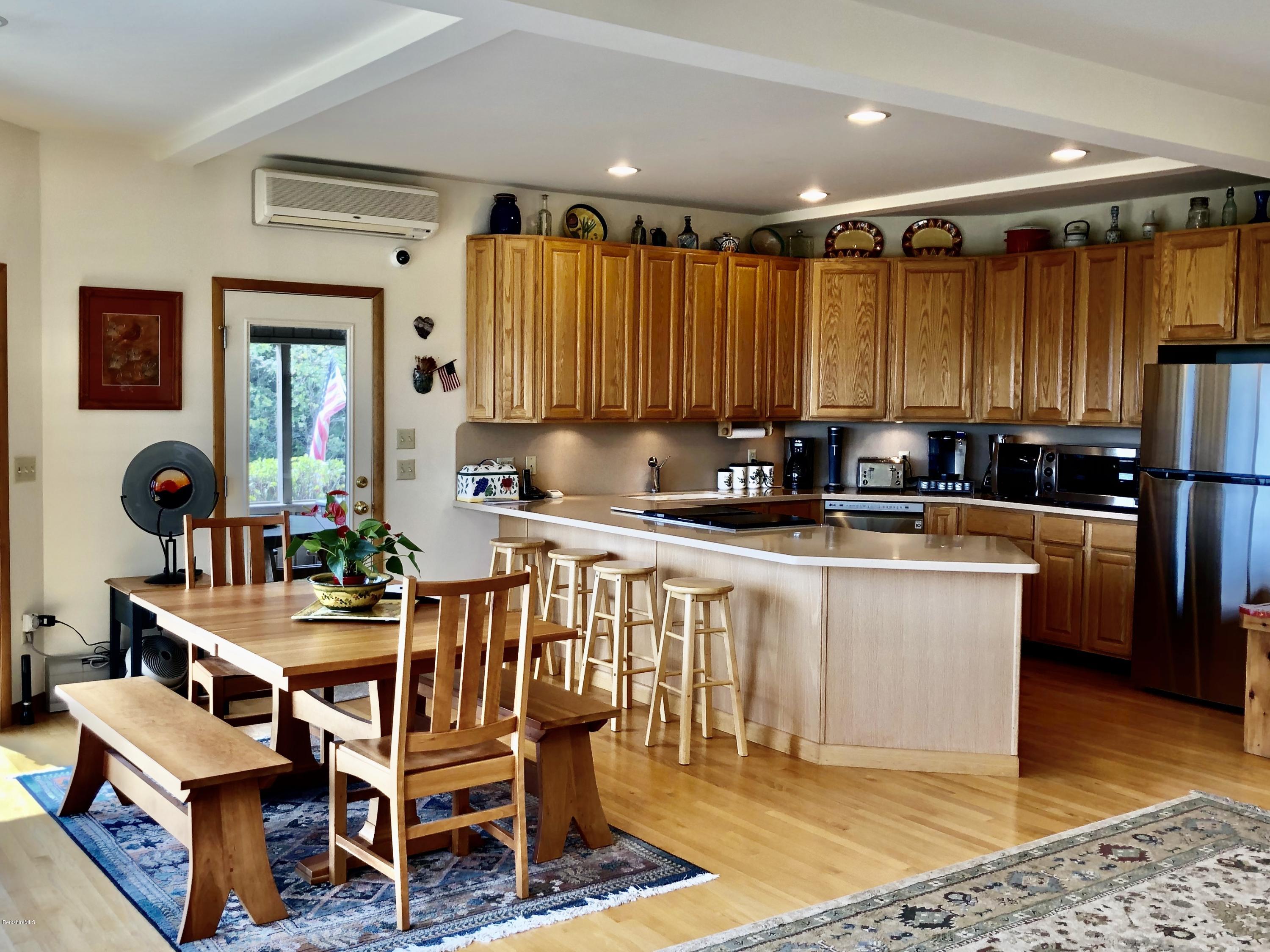 359 Harrington Road Otis, MA 01253 - Photo 19 of 60 a kitchen with granite countertop a table chairs a sink dishwasher refrigerator and cabinets