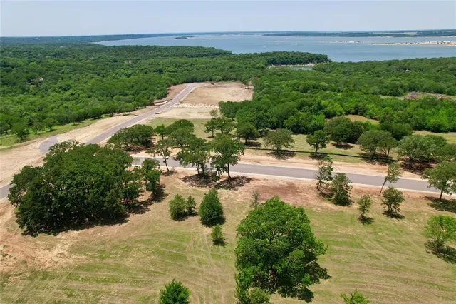 an aerial view of a residential houses with outdoor space and trees all around