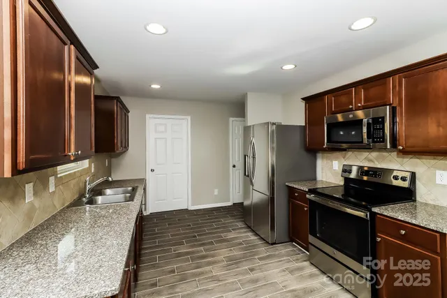 a kitchen with stainless steel appliances granite countertop a stove refrigerator and microwave