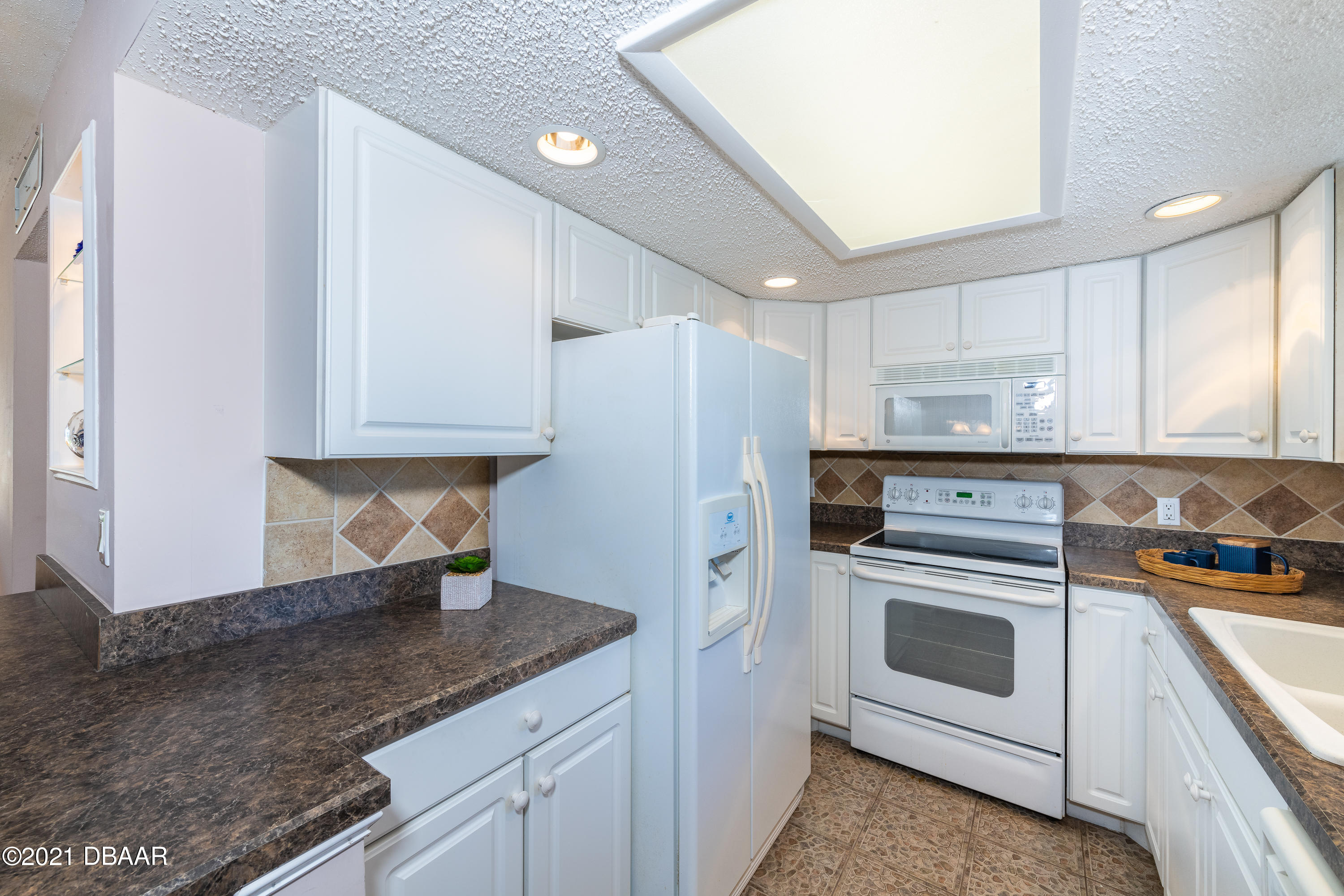 935 Ocean Shore Boulevard, Unit 110 Ormond Beach, FL 32176 - Photo 4 of 21 a kitchen with a stove a sink and a refrigerator