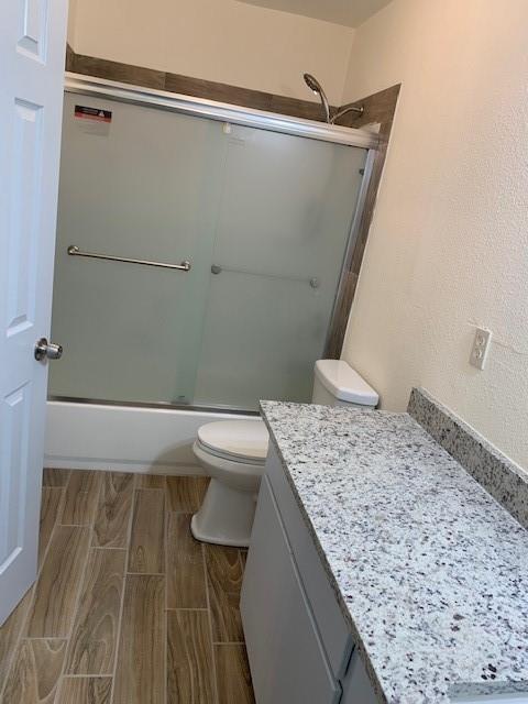 12046 Center Street, Unit 200 Quinlan, TX 75474 - Photo 9 of 9 a bathroom with a granite countertop sink a toilet and shower
