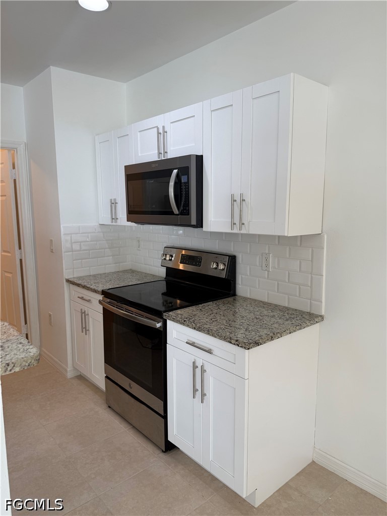 2916 7th Street Southwest Lehigh Acres, FL 33976 - Photo 10 of 19 a kitchen with white cabinets and stainless steel appliances