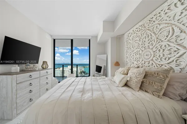 a bedroom with a large bed and a flat tv screen on dresser