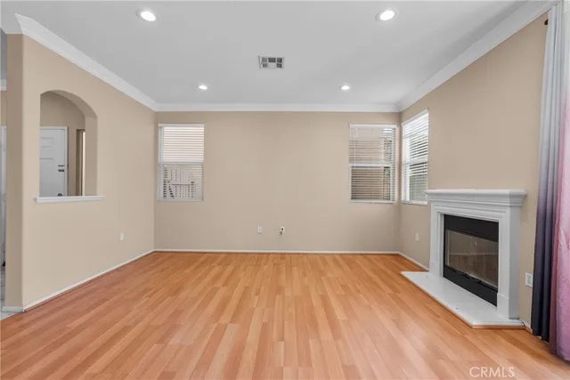 an empty room with wooden floor fireplace and windows