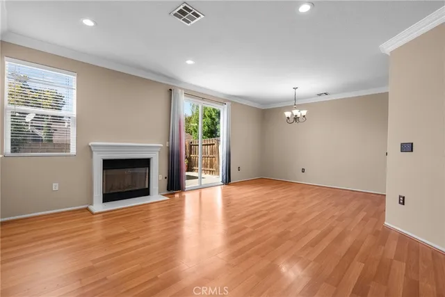 a view of an empty room with wooden floor and a fireplace