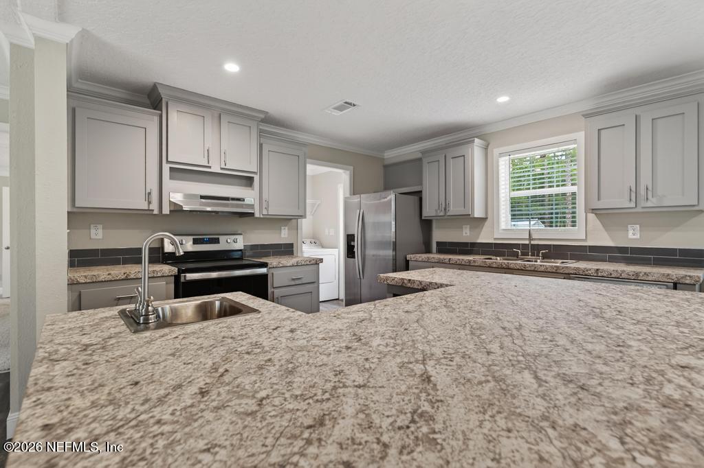 95605 Springhill Road Fernandina Beach, FL 32034 - Photo 17 of 62 a kitchen with stainless steel appliances a stove a sink a refrigerator and white cabinets