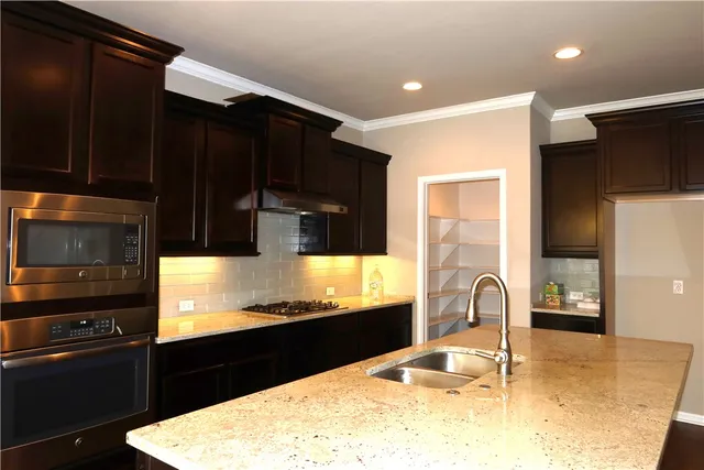 a kitchen with stainless steel appliances kitchen island granite countertop a refrigerator a stove and a sink with wooden floor