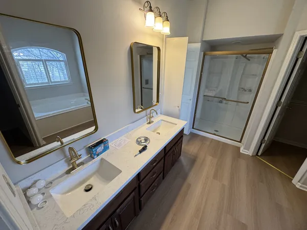 a bathroom with a double vanity sink mirror and tub